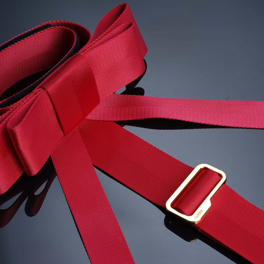 Bowknot Bed Restraint Straps in red with gold buckle, designed for secure and playful restraint on a sleek surface.