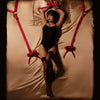 Woman in a black outfit secured with red Bowknot Bed Restraint Straps on a satin bed, creating an alluring scene.